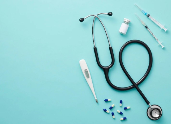 Stethoscope pills and thermometer on blue background