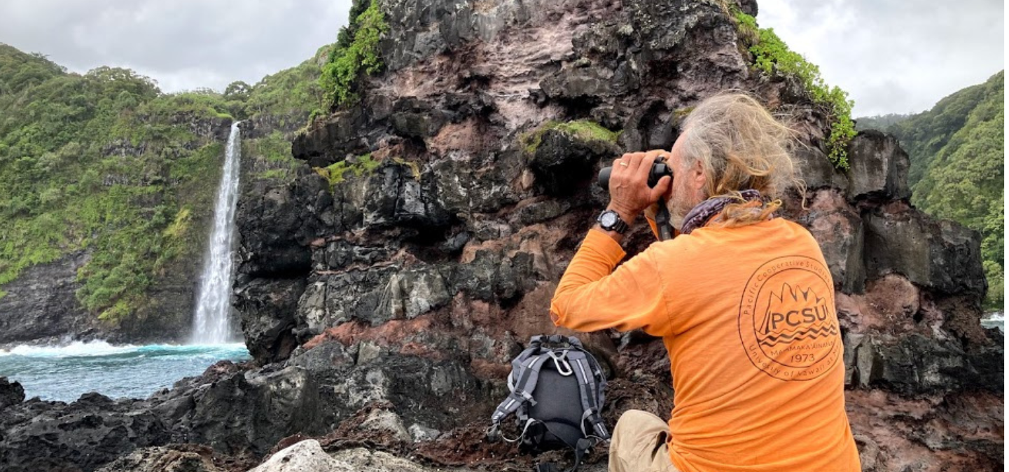 Man looking through binoculars near waterfall